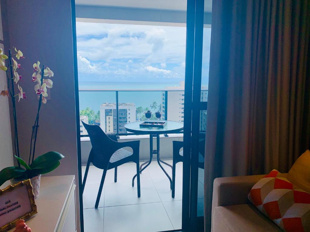 Habitación con mesa y balcón con vistas. en LUXO 1406 - Quarto e Sala com Varanda Frente Mar Ponta Verde, en Maceió