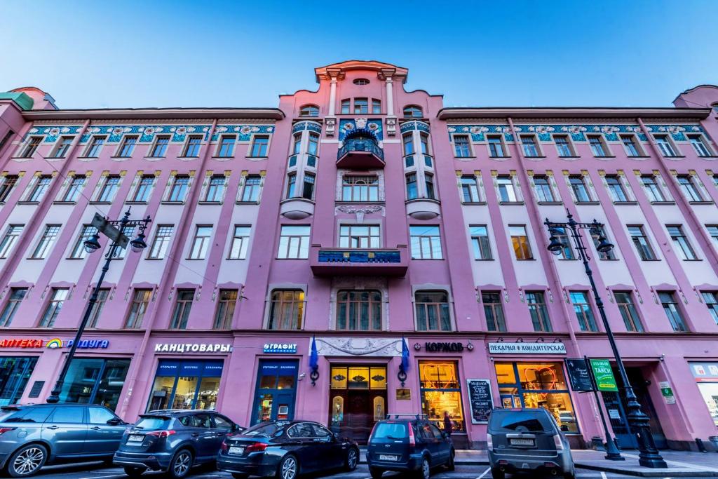 un edificio rosa con coches estacionados frente a él en Akyan St.Petersburg, en San Petersburgo