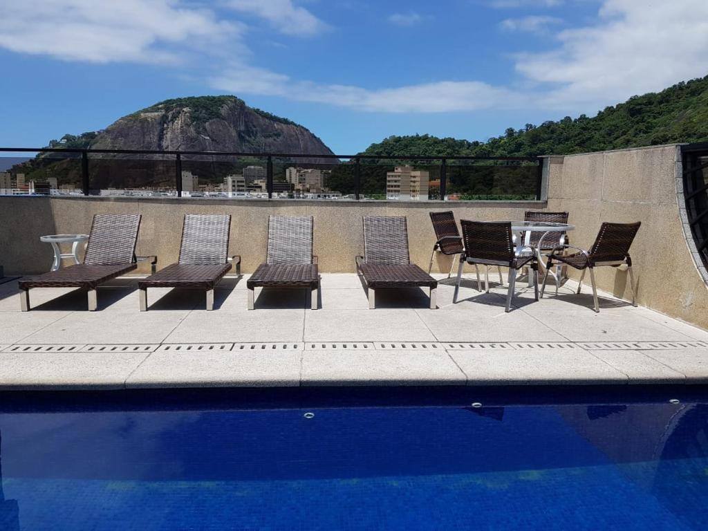 un grupo de sillas y una mesa junto a una piscina en Majestic Rio Palace Hotel, en Río de Janeiro