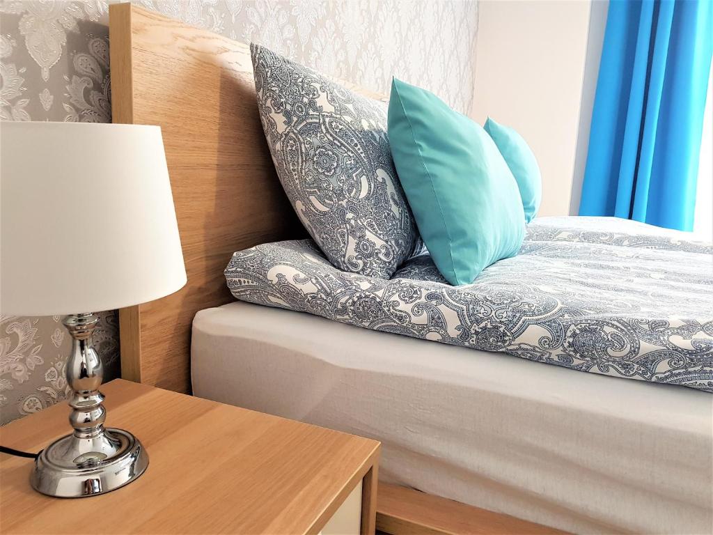 ein Bett mit zwei Kissen und einem Tisch mit einer Lampe in der Unterkunft Apartament B&F Poznań Business & Family in Posen
