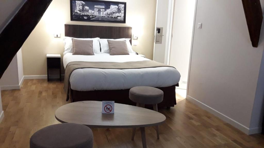 パリにあるオテル マザグランのテーブルとテーブルシックスシックス付きのベッドが備わる小さな客室です。