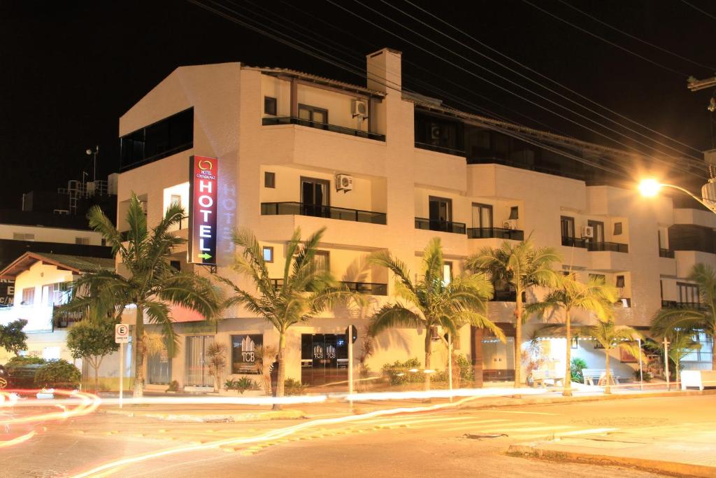 a white building with palm trees in front of it at Hotel Costa Dalpiaz in Torres