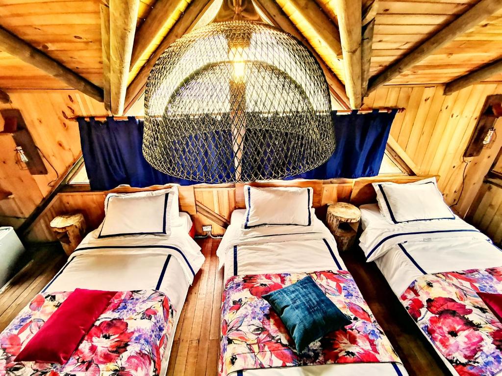 three beds in a room with a chandelier at Palmas de Cocora in Salento