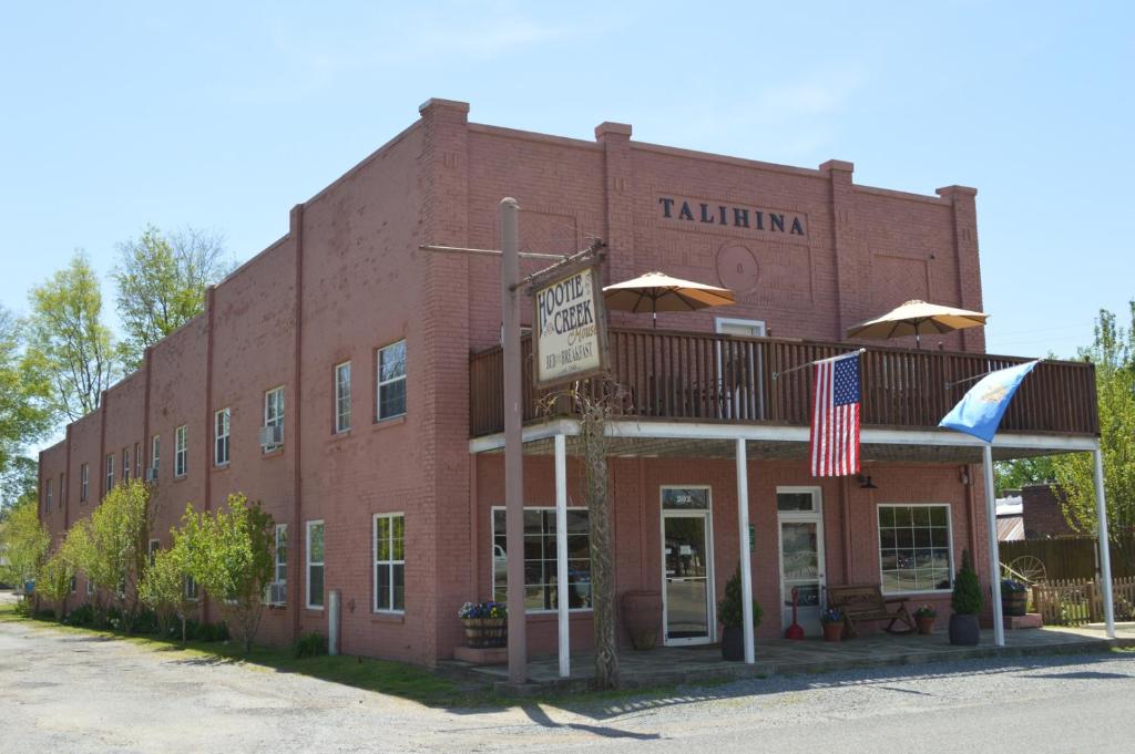 a red brick building with a balcony and an american flag at Hootie Creek Guest House in Talihina