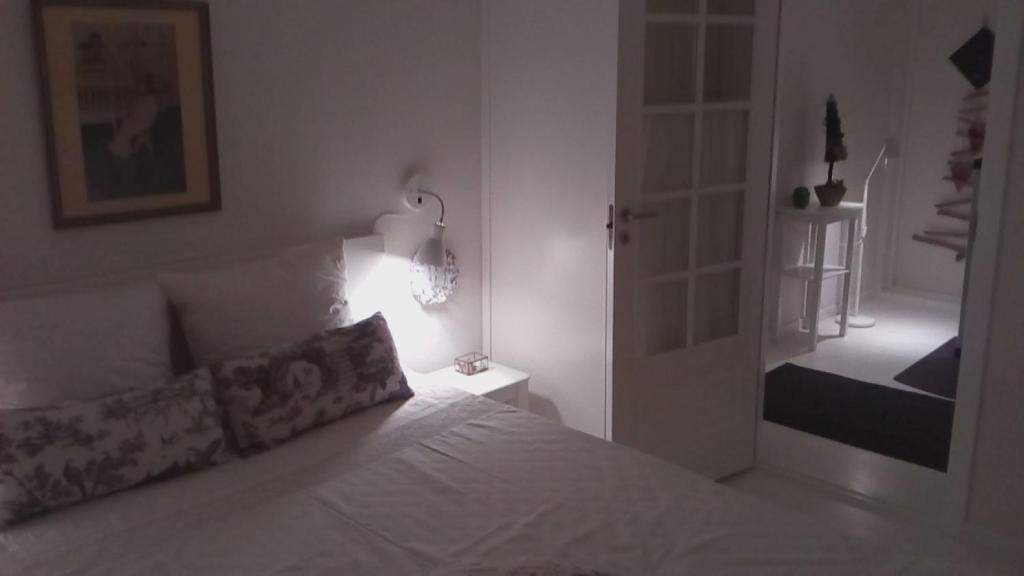 a bedroom with a white bed with a lamp and a door at Hos Anna in Roskilde
