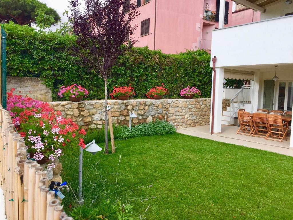 einen Garten mit Blumen und einer Steinmauer in der Unterkunft Villetta Marina in Marciana Marina