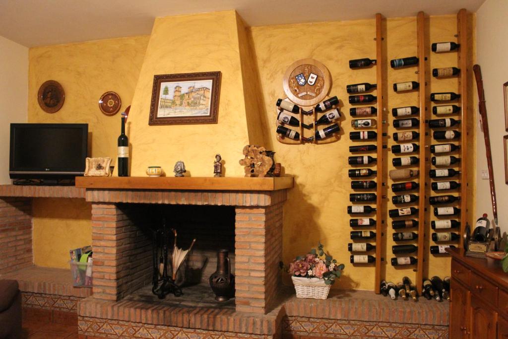 una chimenea en la sala de estar con una estantería de botellas de vino en CASA RURAL BUENA VENTURA, en Villanueva de los Infantes