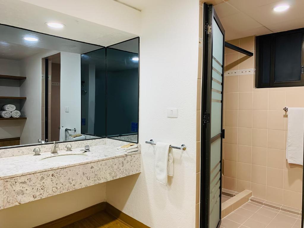 A bathroom with a marble-look vanity, large mirror, and enclosed shower.