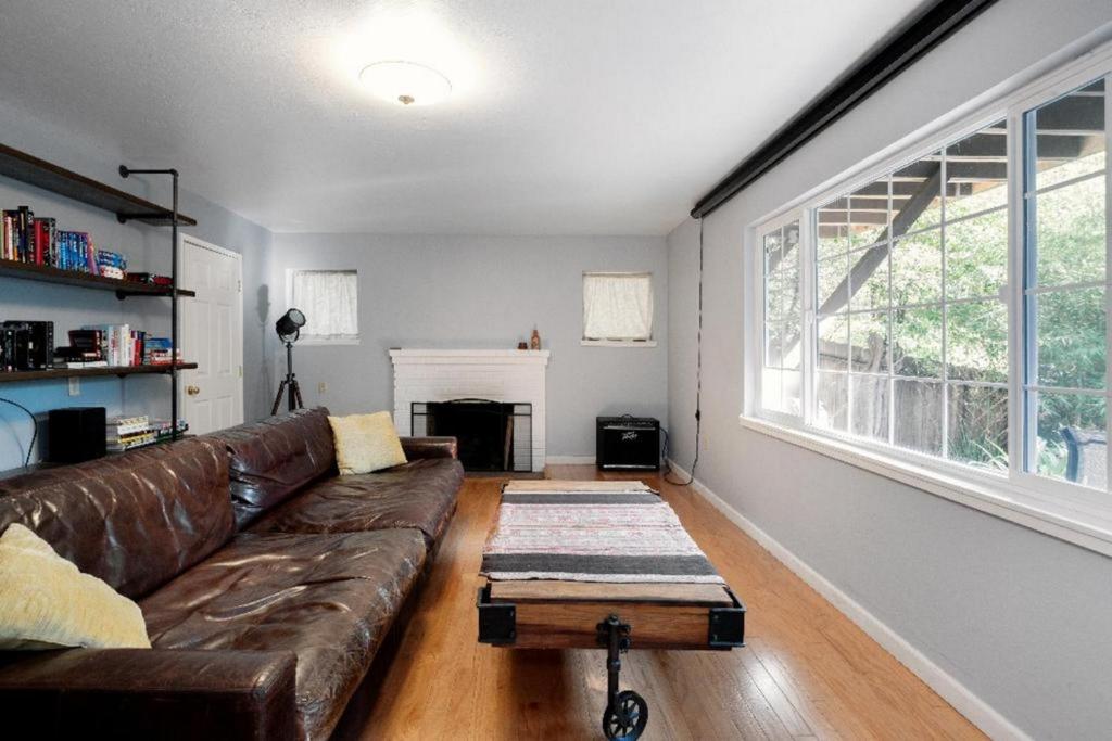 a living room with a brown leather couch and a table at Large 1 Bedroom Apartment, Home Theater, Fireplace in Berkeley