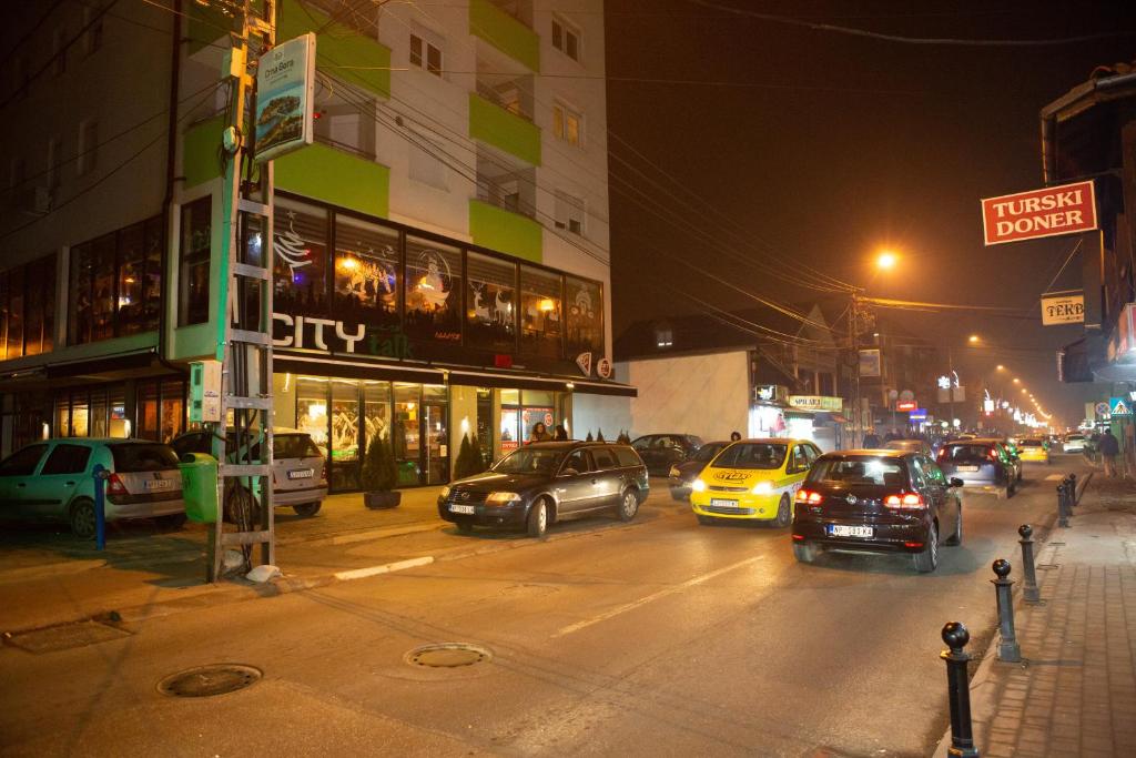 Novi Pazar Apartman lux في نوفي بازار: شارع المدينة مزدحم ليلاً مع وقوف السيارات