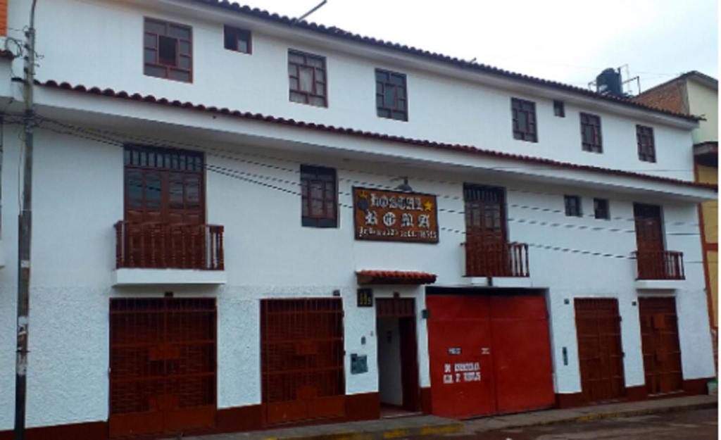 un edificio blanco con puertas rojas y un cartel en él en Hostal Roma en Ayacucho