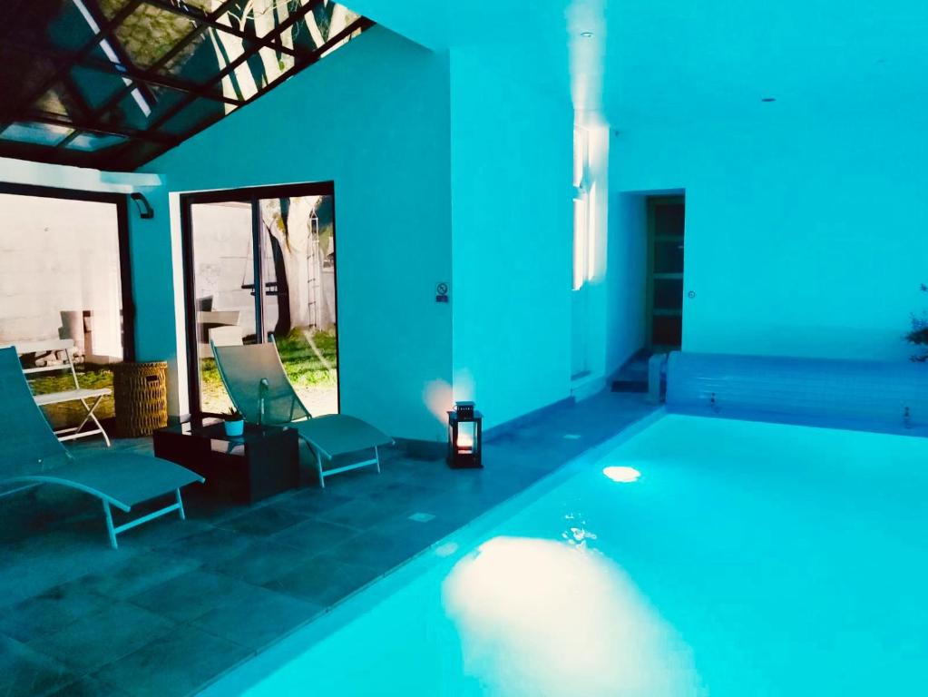 een zwembad in een kamer met blauwe muren en stoelen bij Le 3 fuscien in Amiens