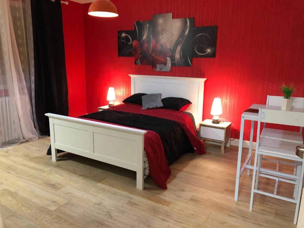 a bedroom with a red wall with a bed and a table at Chambres privées Calais Ferry-Port-Place d&#39;armes in Calais