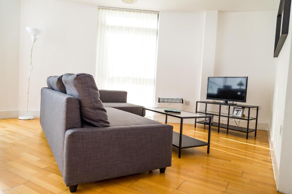 a living room with a couch and a tv at Serviced Apartment In Liverpool City Centre - Free Parking - Balcony - by Happy Days in Liverpool