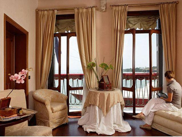 a woman sitting in a living room looking out the window at B&B La Rosa dei Venti in Venice