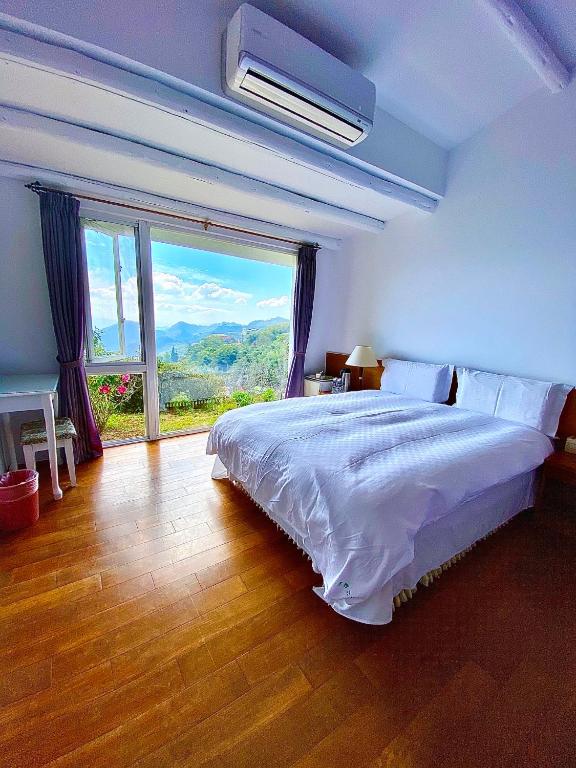 a bedroom with a large bed and a large window at Alishan Tea Garden B&amp;B in Fenqihu