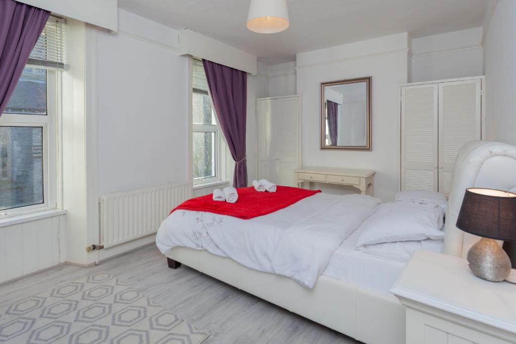 a white bedroom with a white bed with a red blanket at Windsor House in Derry Londonderry