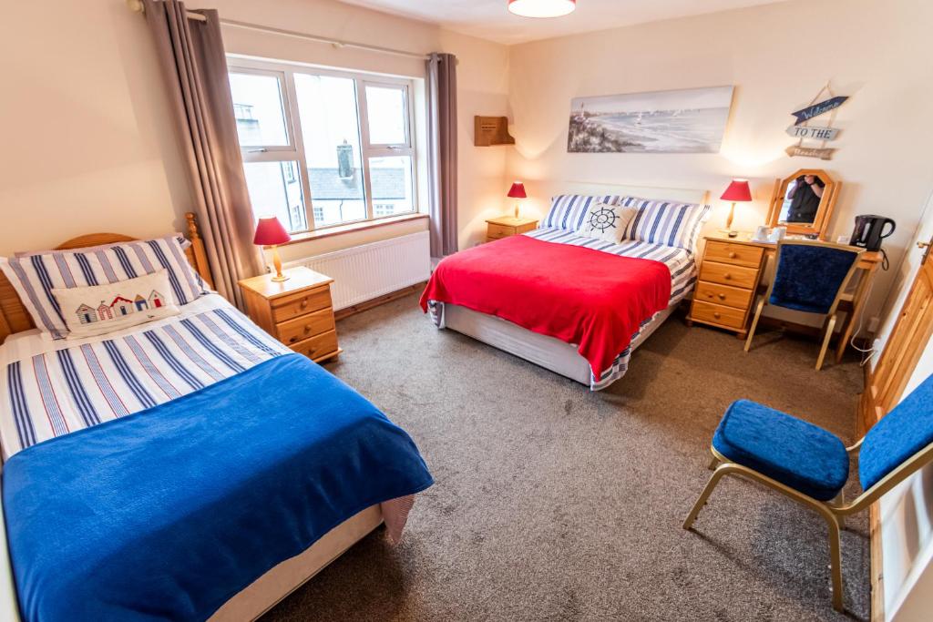 a bedroom with two beds and a chair and a window at Seawinds Bed and Breakfast in Killybegs
