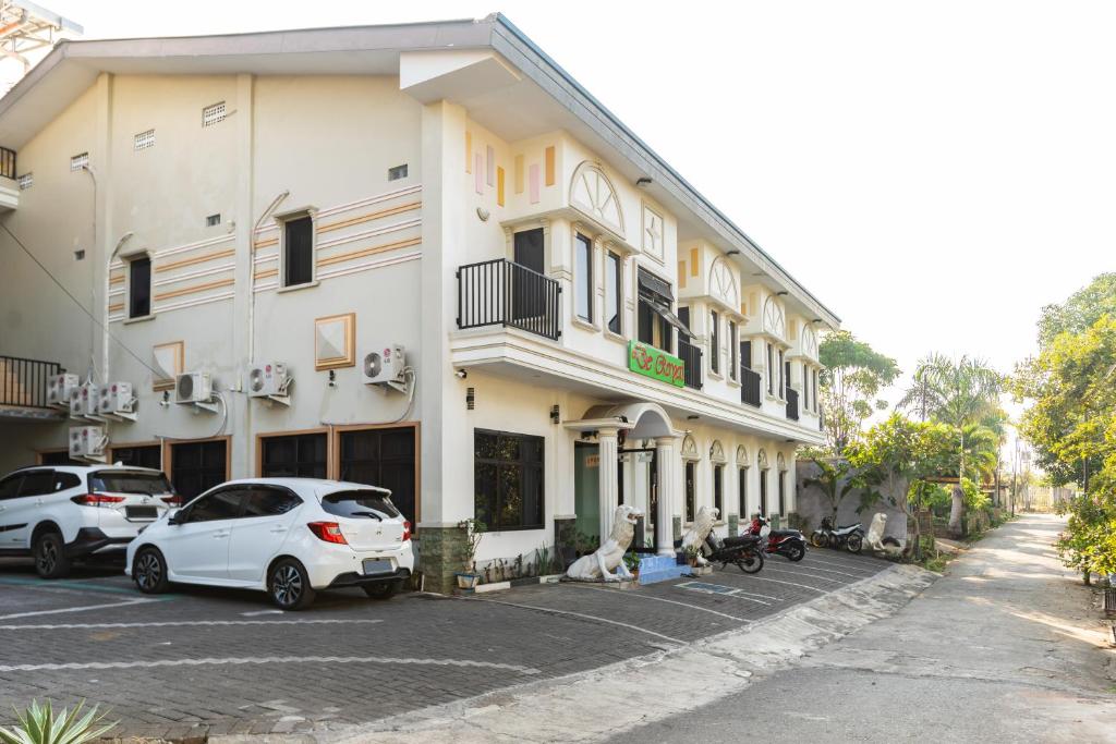 un bâtiment blanc avec des voitures garées dans un parking dans l'établissement RedDoorz Plus @ Jalan Pumorow Manado, à Manado