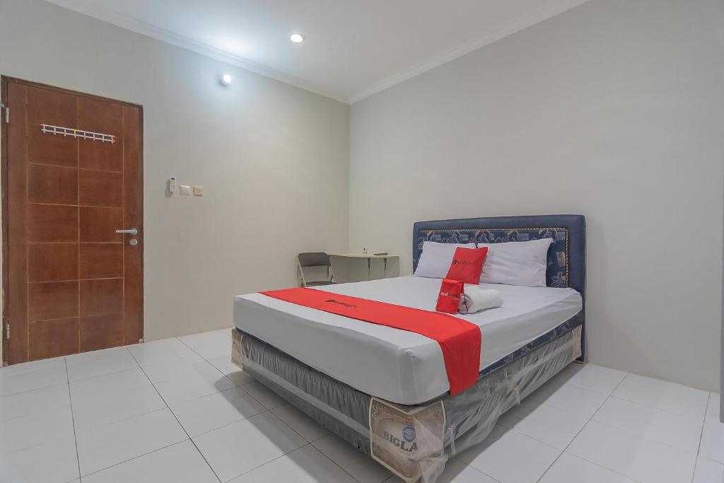 a bedroom with a bed and a wooden door at RedDoorz Plus at Bukit Cinta Street Balikpapan in Klandasan Kecil