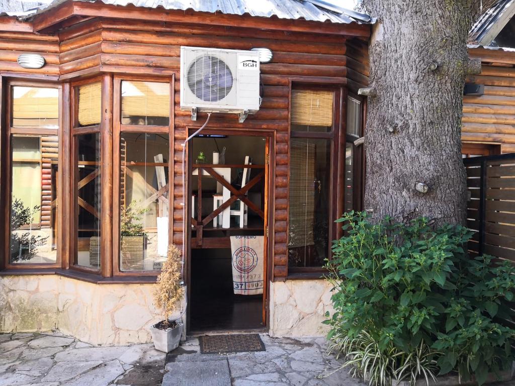 uma casa de madeira com uma porta e uma árvore em Depto Boutique LA ALDEITA em Sierra de los Padres