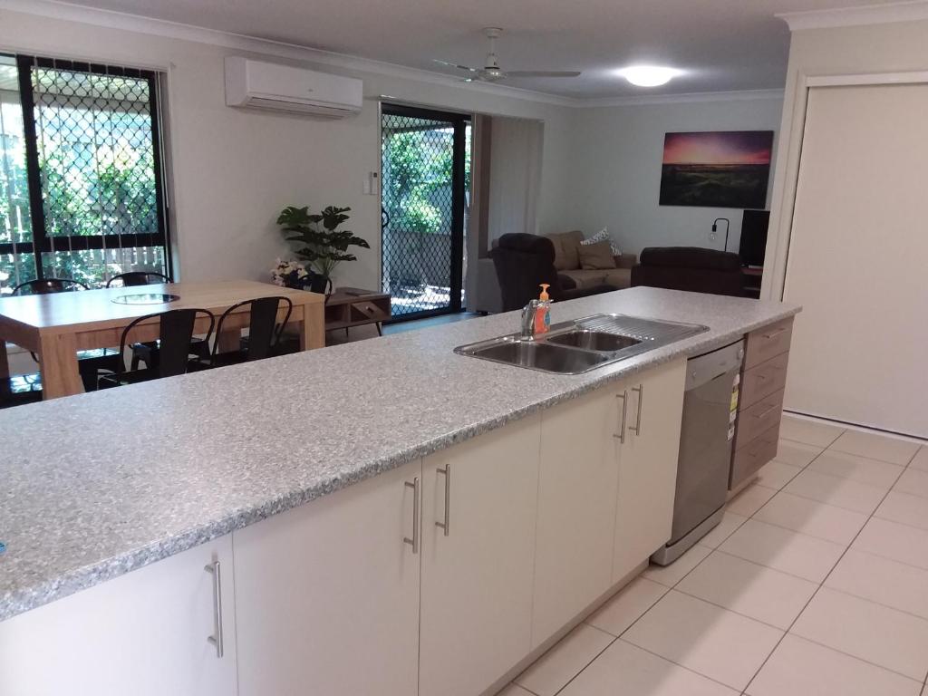 a kitchen with a sink and a living room at Waratah and Wattle Apartments in Maryborough