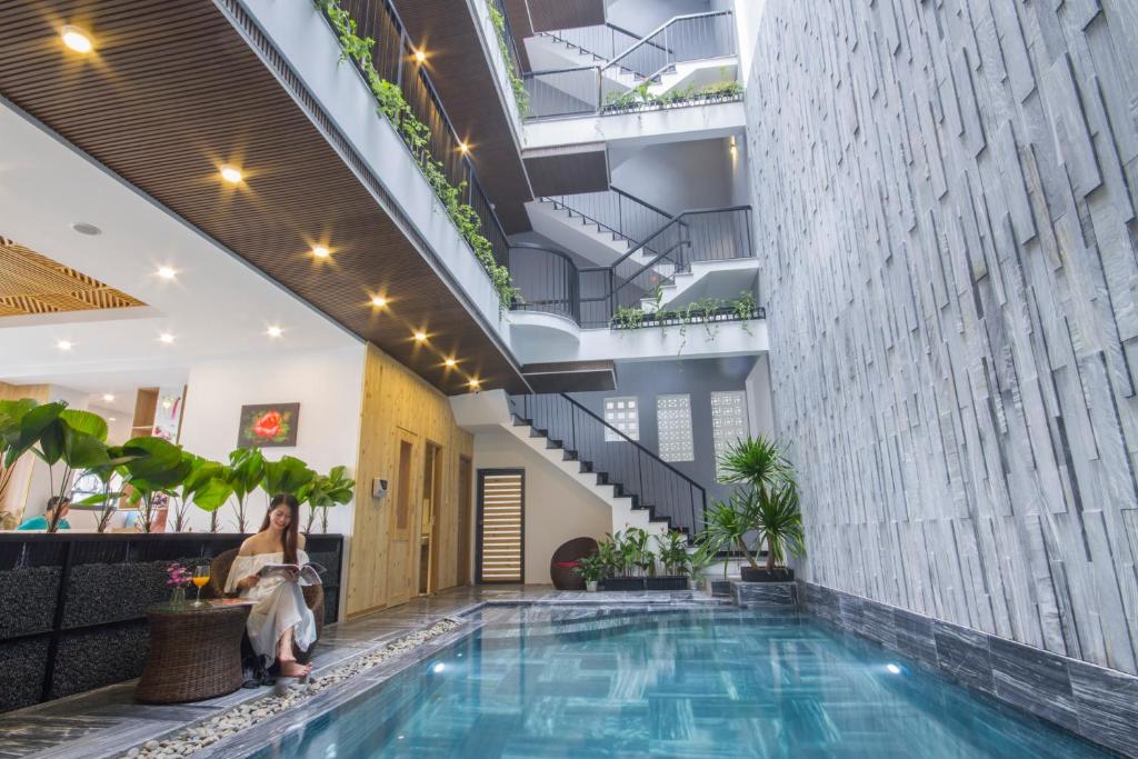 A narrow indoor courtyard pool beneath planted balconies and a tall textured wall.