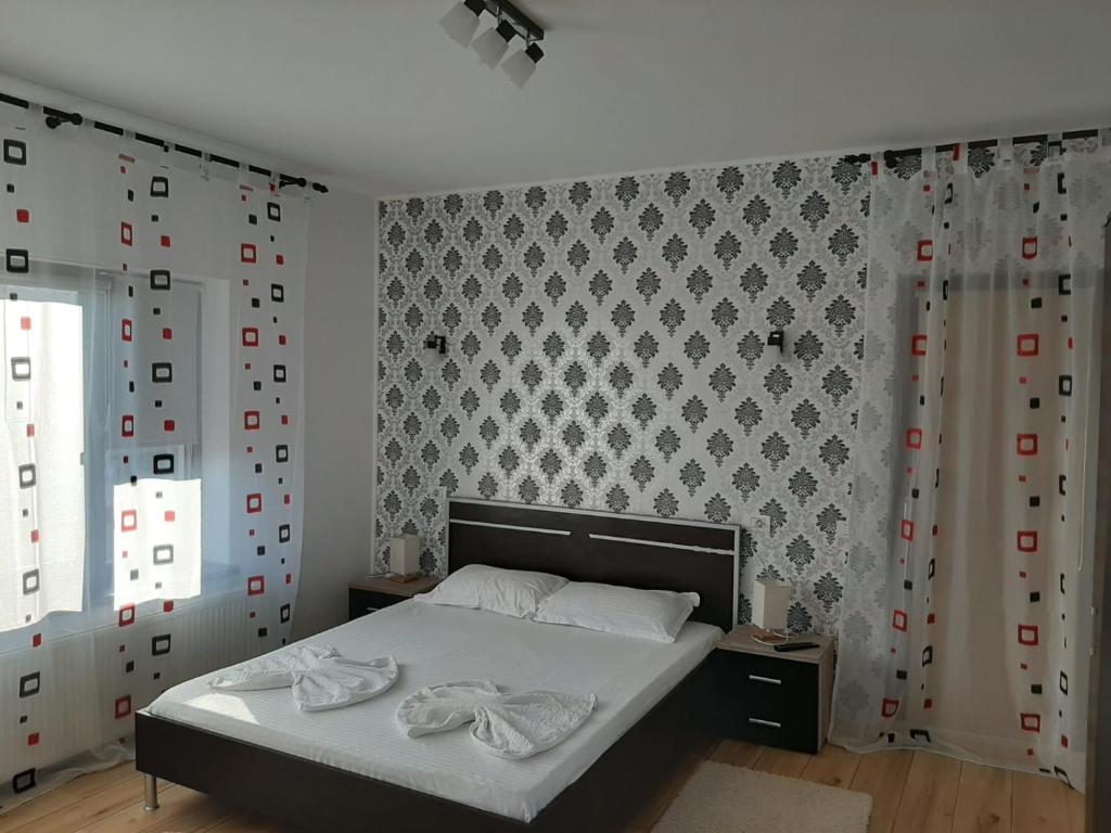 Cette chambre comprend un lit avec des draps blancs et un mur. dans l'établissement Pensiunea Turist, à Techirghiol