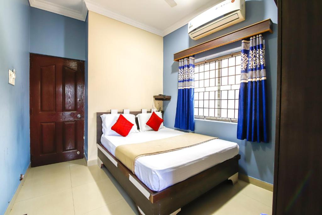 a bedroom with a bed with blue walls and a window at Lusia Inn in Bangalore