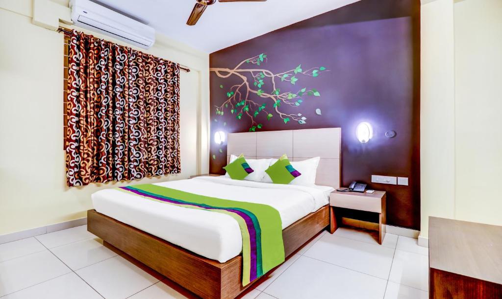 Treebo Trend Petals Suites Ernakulam Town في كوتشي: غرفة نوم بسرير كبير ونافذة