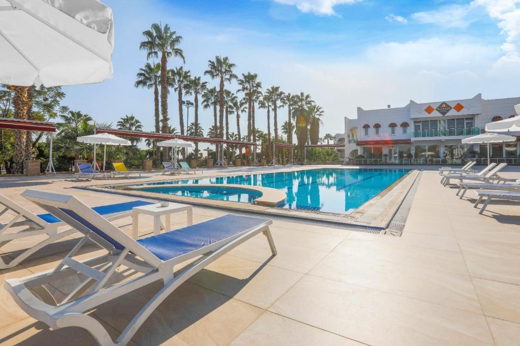 ein Pool in einem Resort mit Liegestühlen und Palmen in der Unterkunft Sultasa Hotel in Mersin