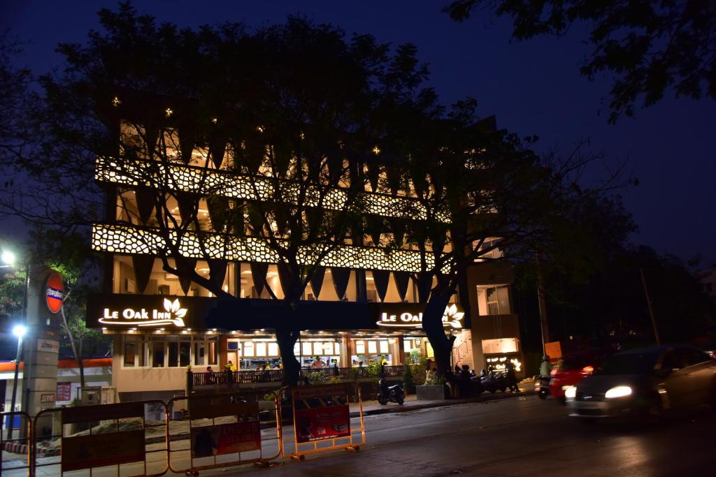 a building with a tree in front of it at night at Le Oak Inn in Mysore