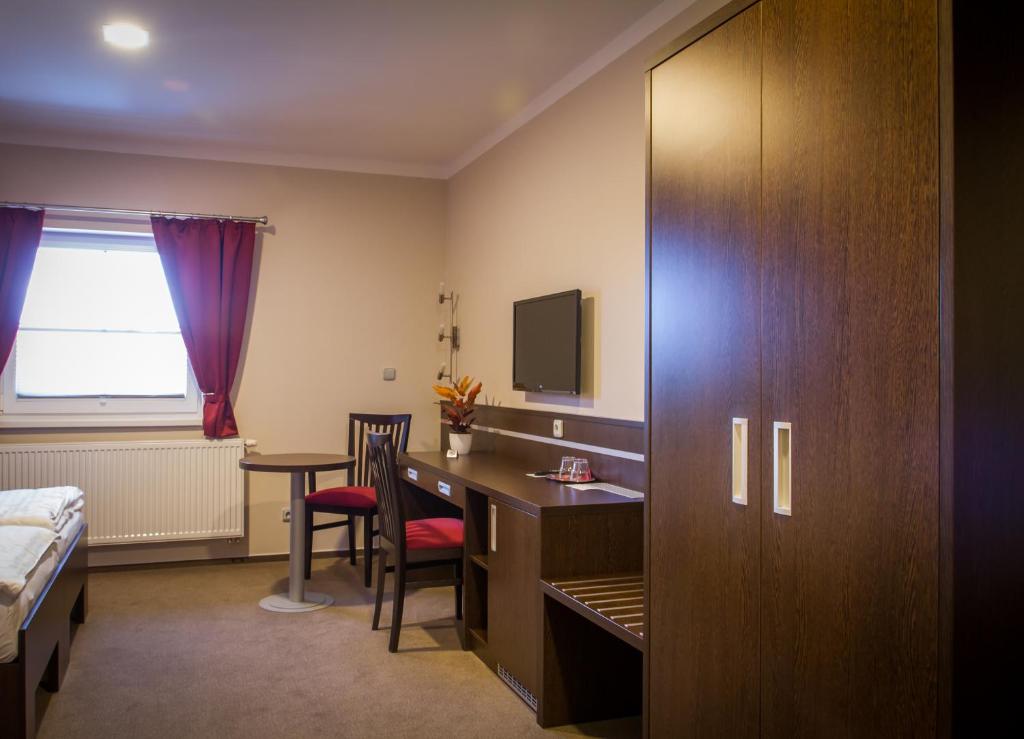 a hotel room with a desk and a bed at Penzion Na Netřebě in Pardubice