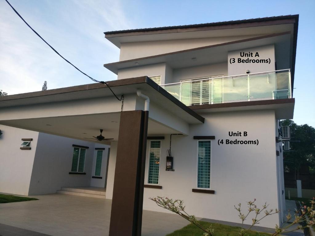 Uma casa branca com dois sinais. em Villa DSelasih Homestay @UMT UNISZA em Kuala Terengganu