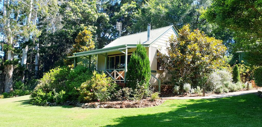 una piccola casa in un cortile con un prato verde di Bendles Cottages a Maleny