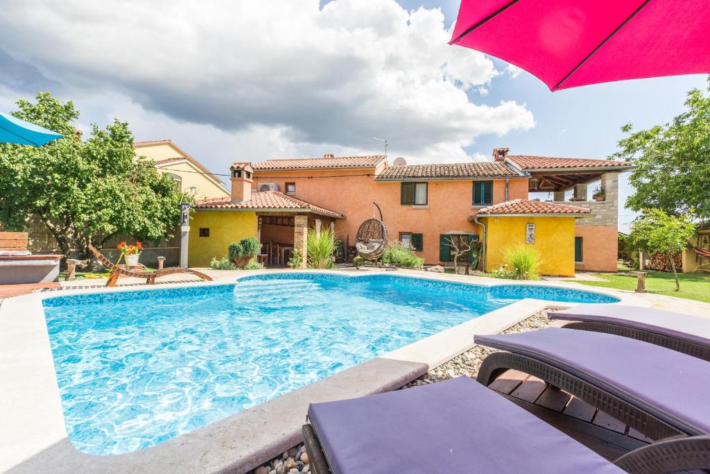 a swimming pool in front of a house with an umbrella at Beautiful villa Loreta with private pool near Pula and Rovinj in Čabrunići