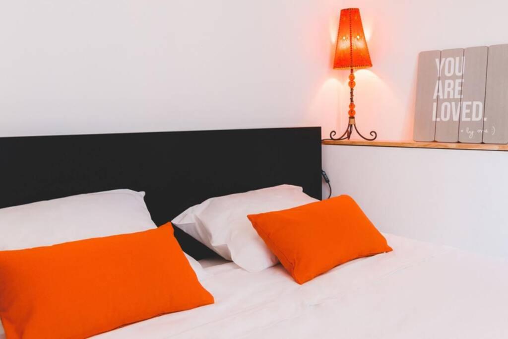 uma cama com almofadas laranja e branca e um candeeiro em Welcome to Alcântara Apartment em Lisboa