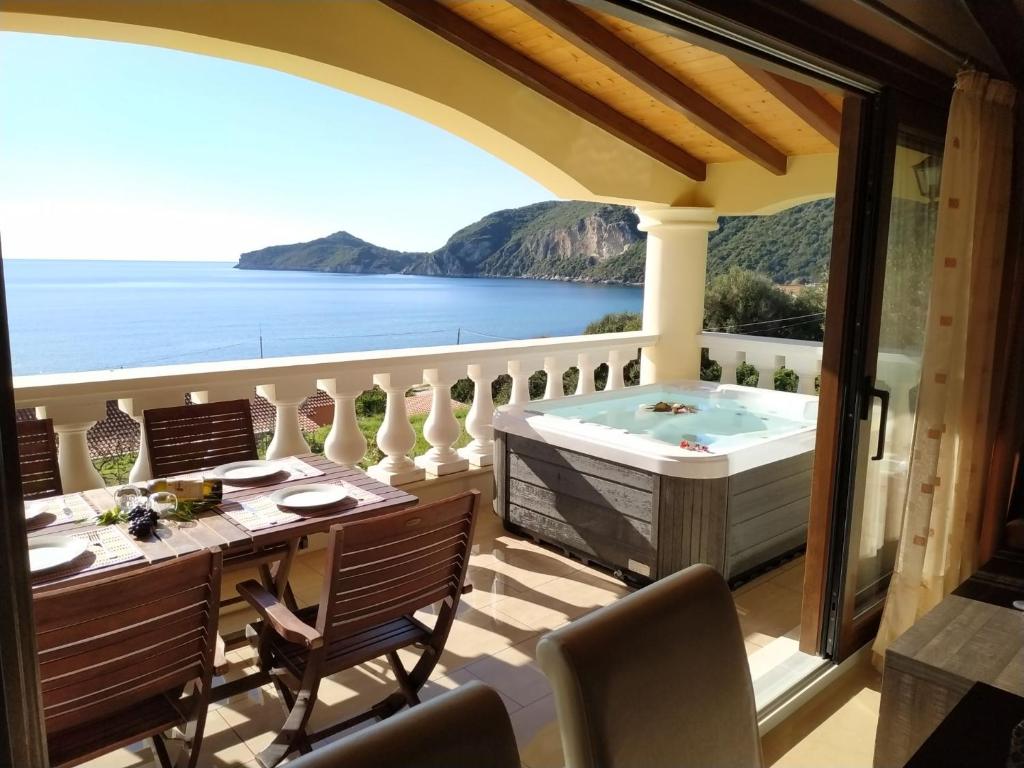 a balcony with a hot tub and a table and chairs at Corfu Maisonettes Anemouri - San George Apartments in Agios Georgios Pagon