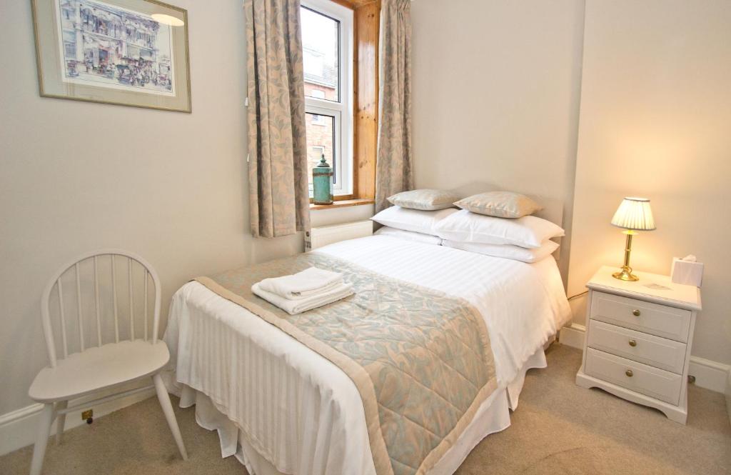 a bedroom with a bed and a chair and a window at The Hedley Townhouse in Bournemouth