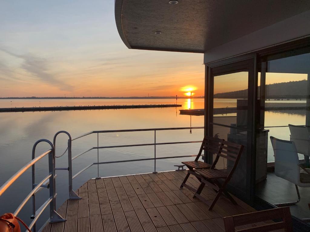 einen Balkon eines Bootes mit Sonnenuntergang auf dem Wasser in der Unterkunft Hausboote Marina Braunsbedra in Braunsbedra