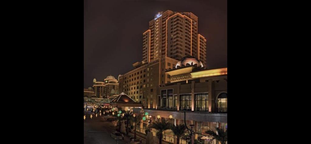 une rue de la ville avec un grand bâtiment la nuit dans l'établissement Resort Suites by Landmark at Bandar Sunway Sunway Lagoon, à Kampong Penaga