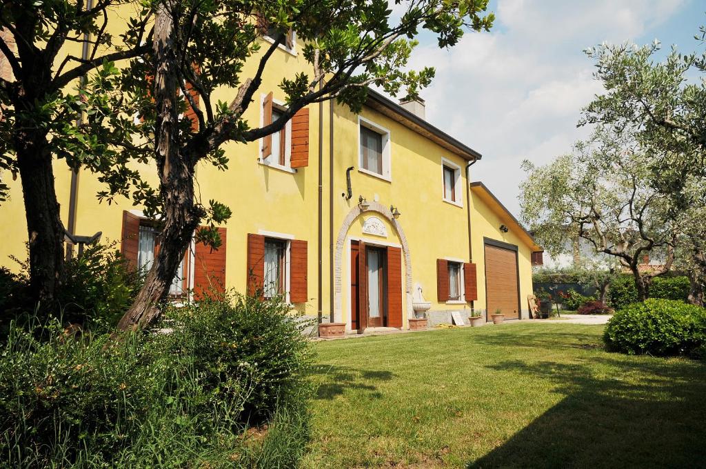 ein gelbes Haus mit einem Baum im Hof in der Unterkunft VILLA CLANI apartment in Colà di Lazise