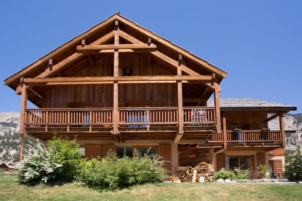 a large log cabin with a wrap around deck at L'Echaillon - Ancolie in Névache