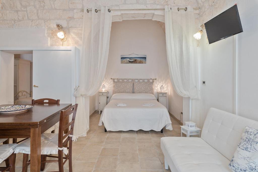 ein weißes Schlafzimmer mit einem Bett und einem Tisch in der Unterkunft White House Flats & Studios in Ostuni