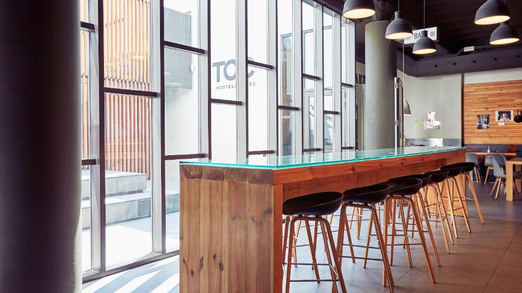 a bar with stools in a room with windows at TOC Hostel Barcelona in Barcelona
