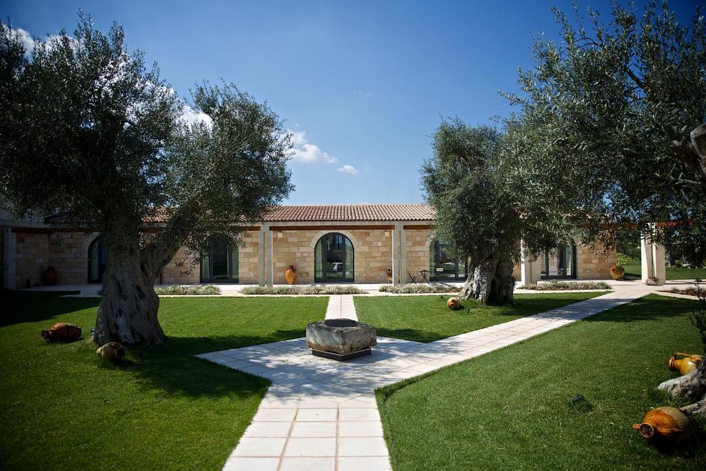 uma casa com duas árvores e uma pedra no quintal em Masseria Stali, The Originals Relais em Caprarica di Lecce