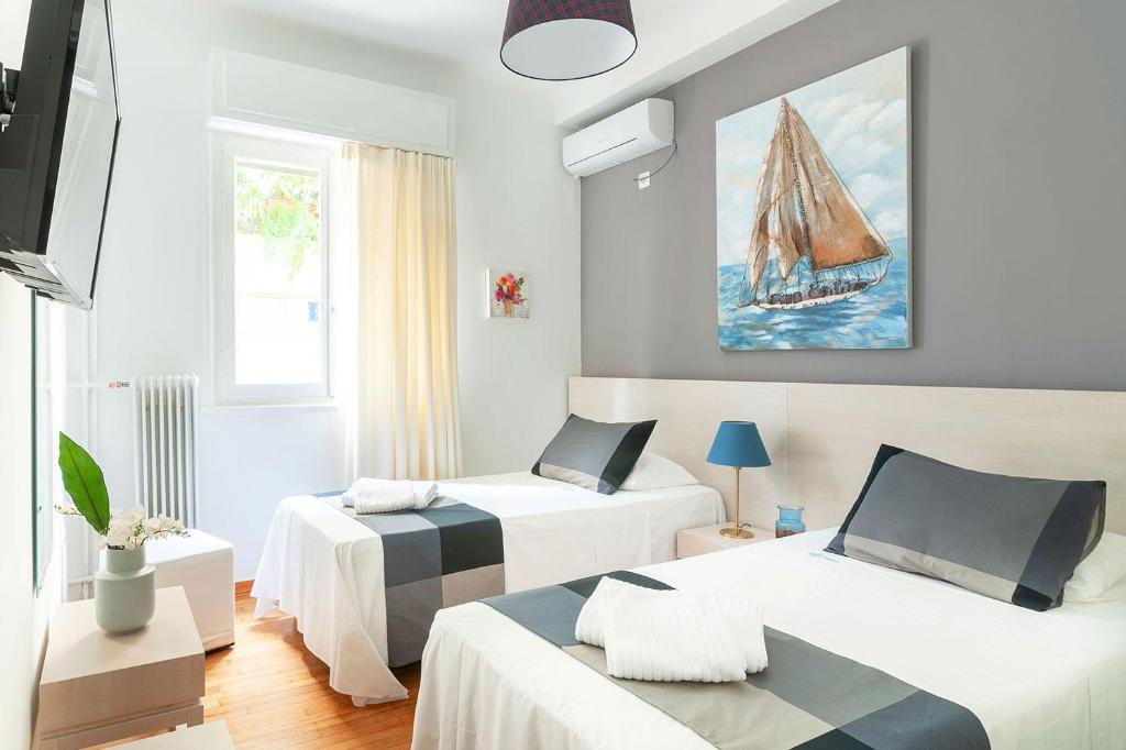 a room with two beds and a painting of a sailboat at Aegle by Heloni Apartments in Athens