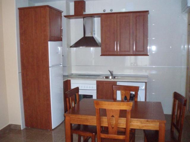 a kitchen with a table and chairs and a refrigerator at Hostal el Altozano in Montánchez