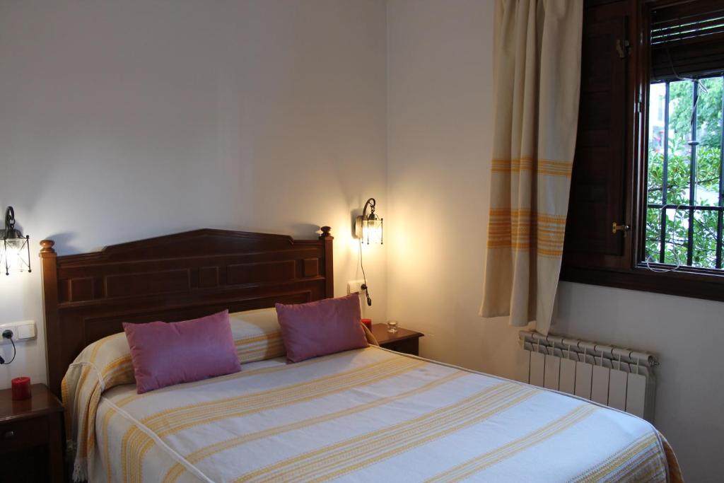 a bedroom with a bed with two purple pillows at Apartamentos Rurales Rosendo: La Canela in Capileira