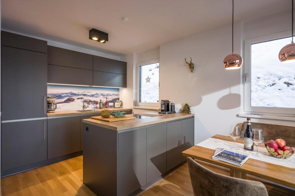 a kitchen with gray cabinets and a wooden table at Goasblick - by NV Appartements in Kirchberg in Tirol